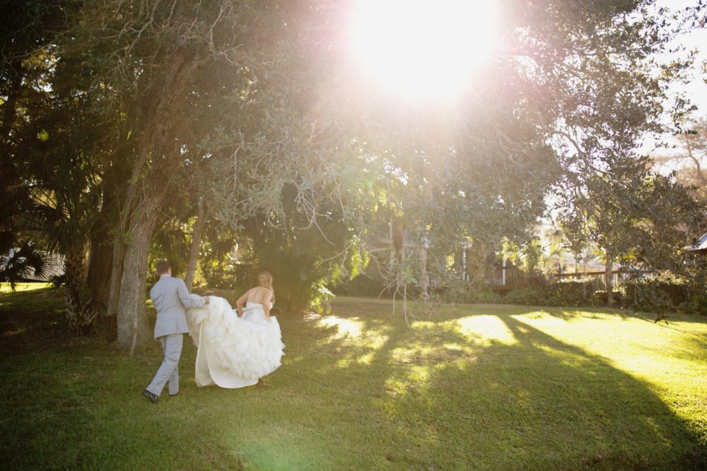 groom holding his brides dress walking away
