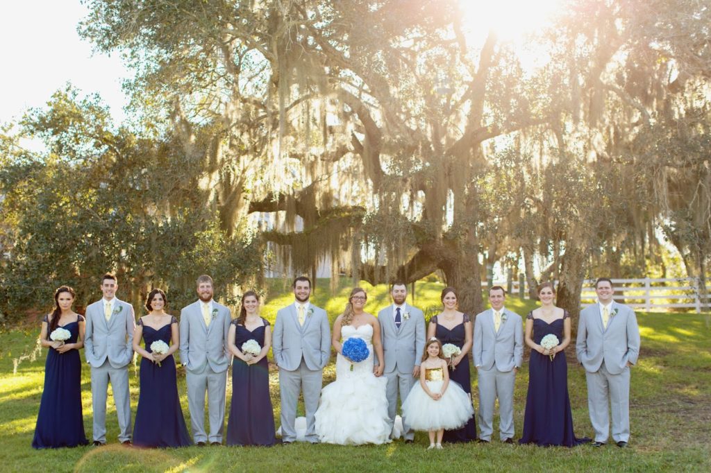 bridal party wearing navy grey and yellow standing under a big oak tree