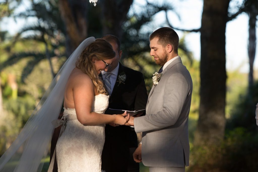 bride placing the ring on the groom and smiling 