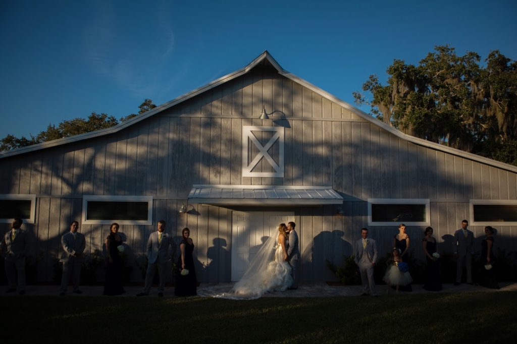 bride and groom kissing while standing in front of a grey barn