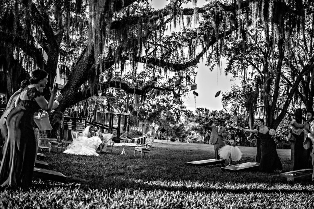 black and white photo of the bridal party playing cornhole