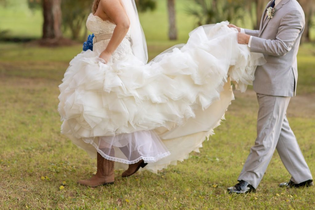 bride wearing boots while her husband holds her dress