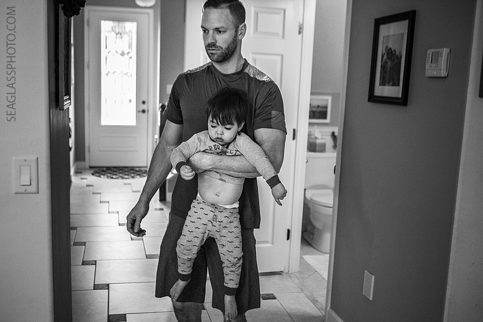 dad carrying the toddler out of the bathroom after playing in the toliet