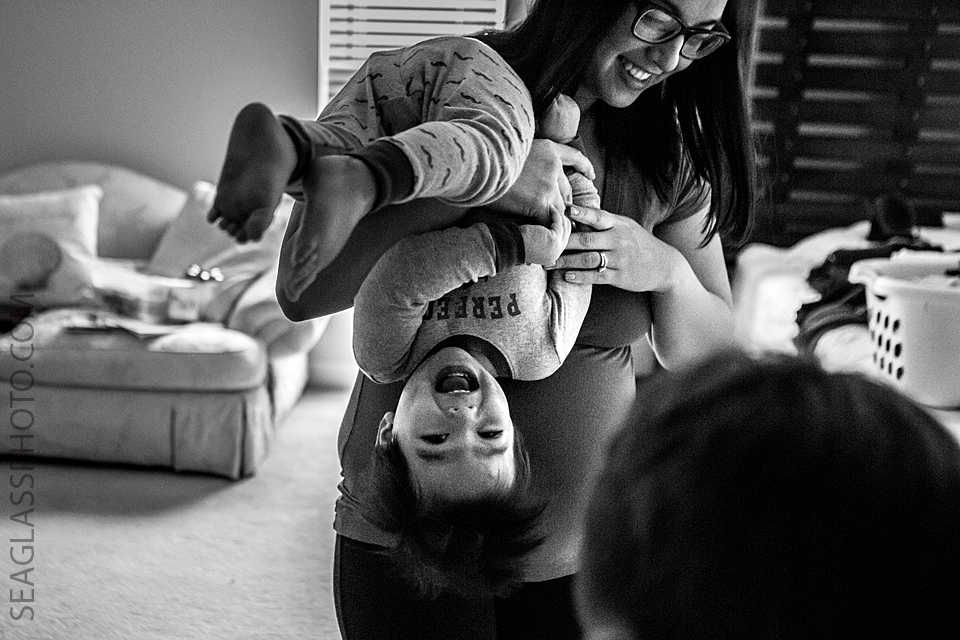 family laughing together as the mom turns the toddler boy upside down