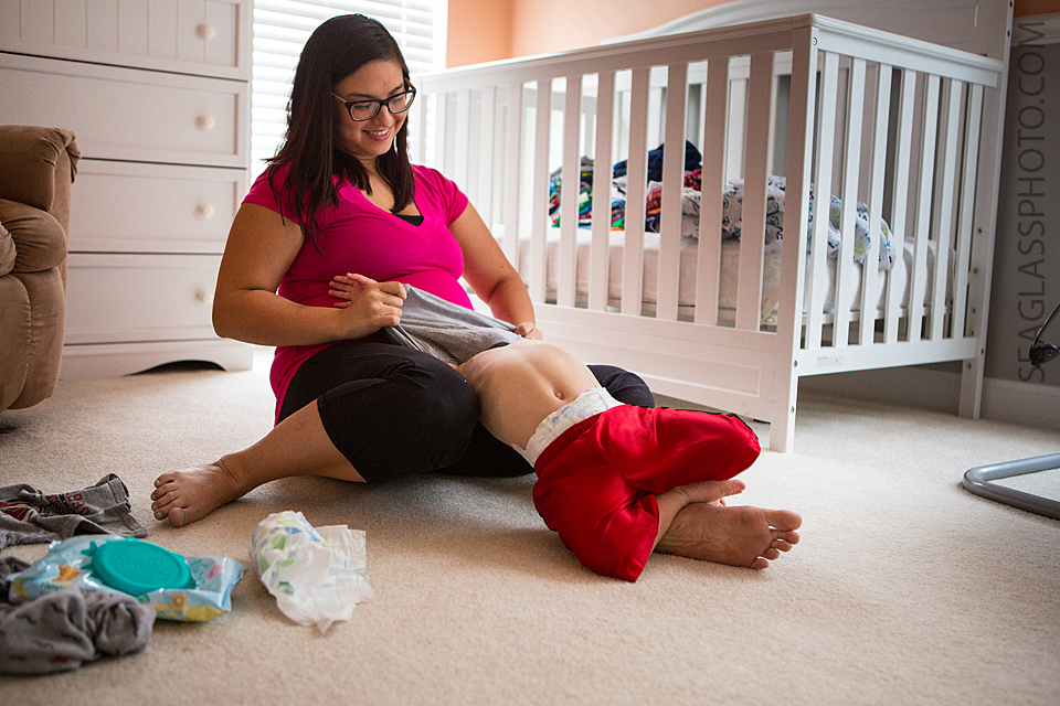 mom laughing as she tries to change her sons clothes