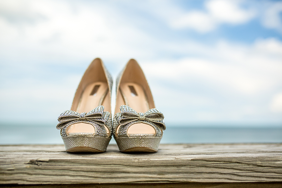 silver wedding shoes sitting on driftwood on the beach in vero