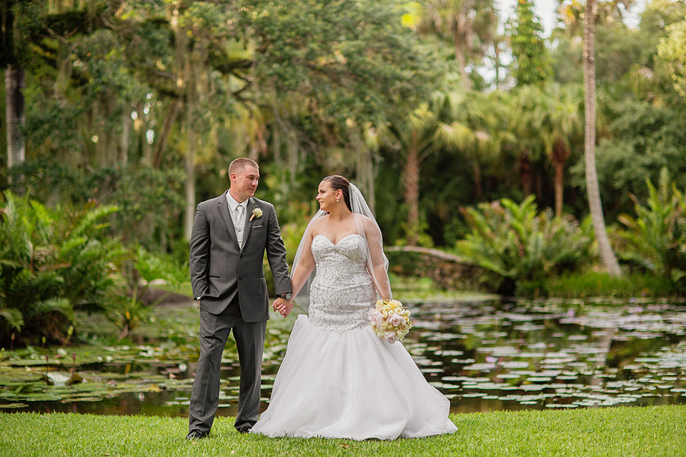 Bride and groom holding hands at mckee gardens standing in front of a pond