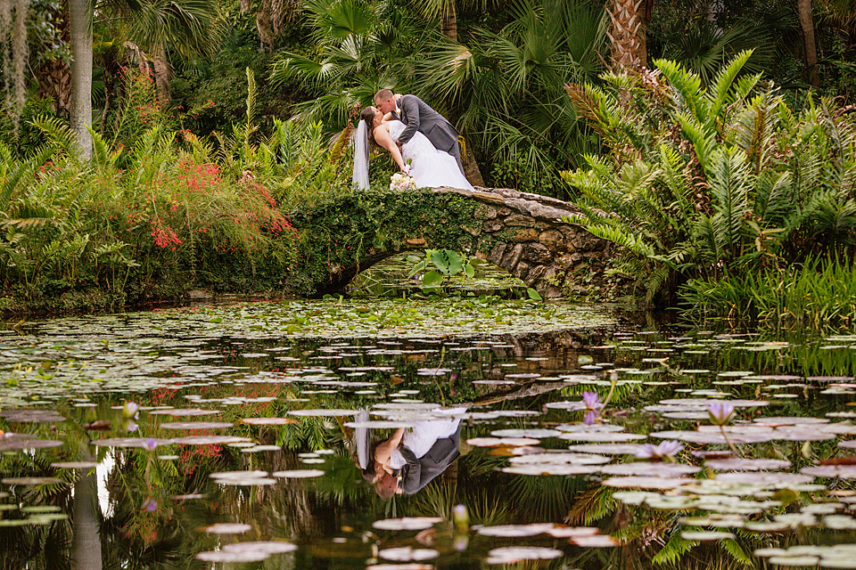 Bride and groom dip kissing on the bridge in mckee gardens 
