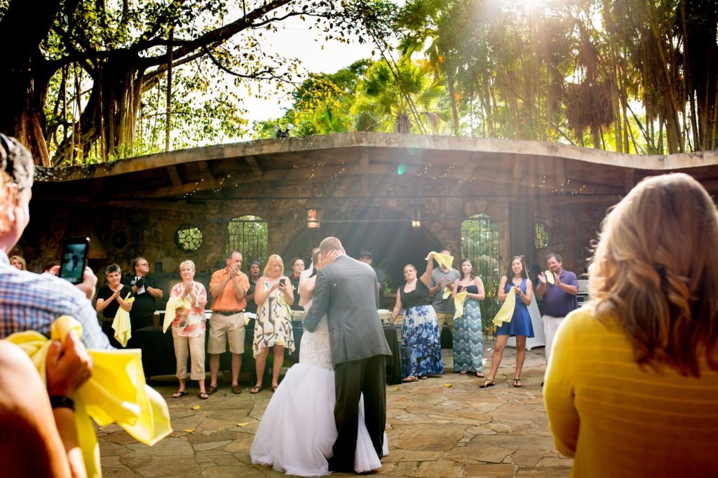 bride and groom have their first dance while being surrounded by guests