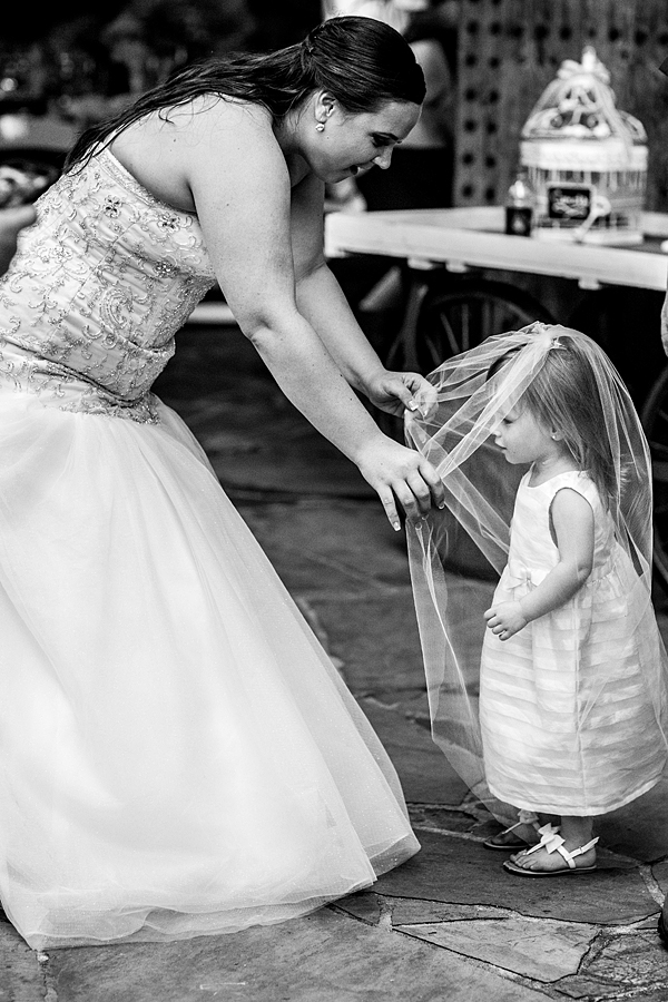 black and white photo of bride putting the viel on the flower girl