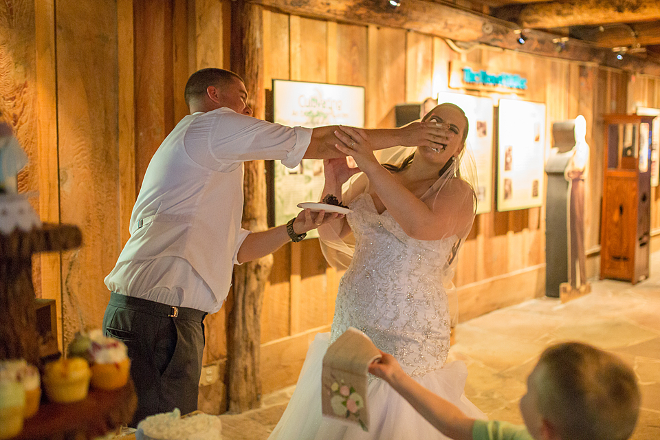 groom smashes the cake in the bride face while a little boy hands her a napkin