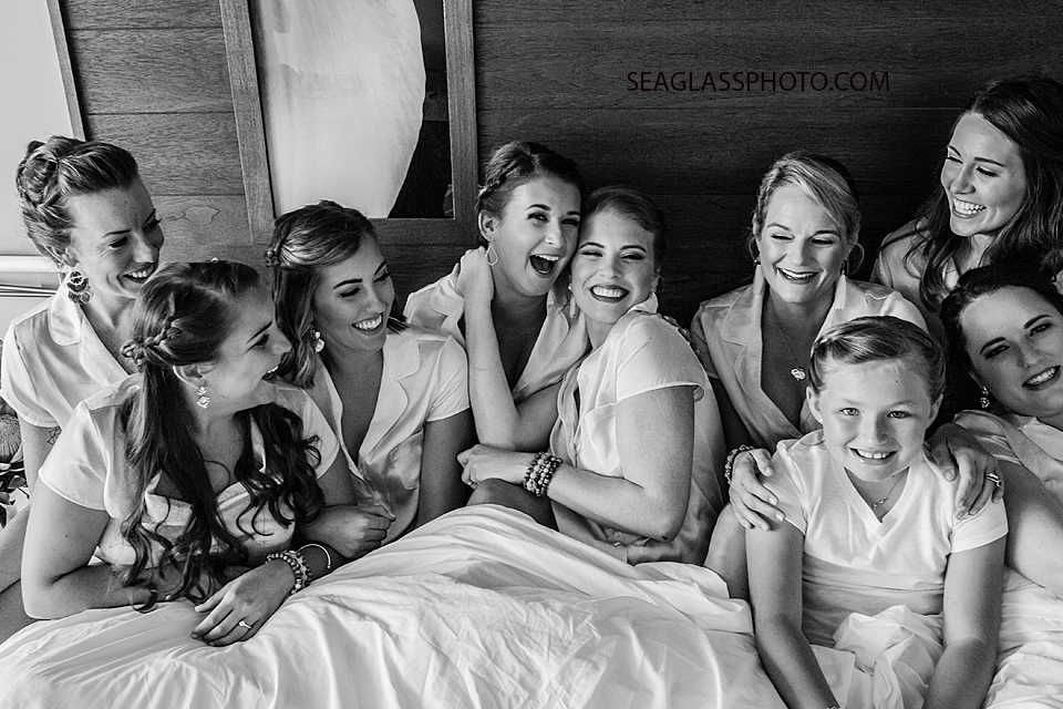 black and white photo of bridal party in bed laughing