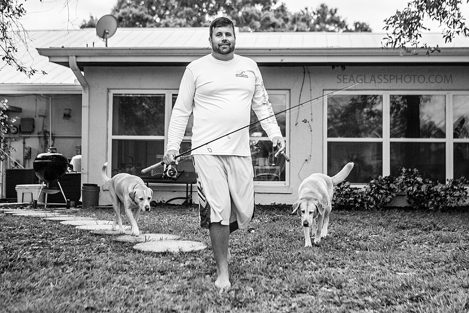 black and white photo of groom going fishing with his two dogs