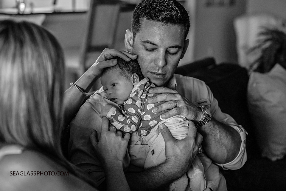 black and white photo of dad holding his baby girl at home