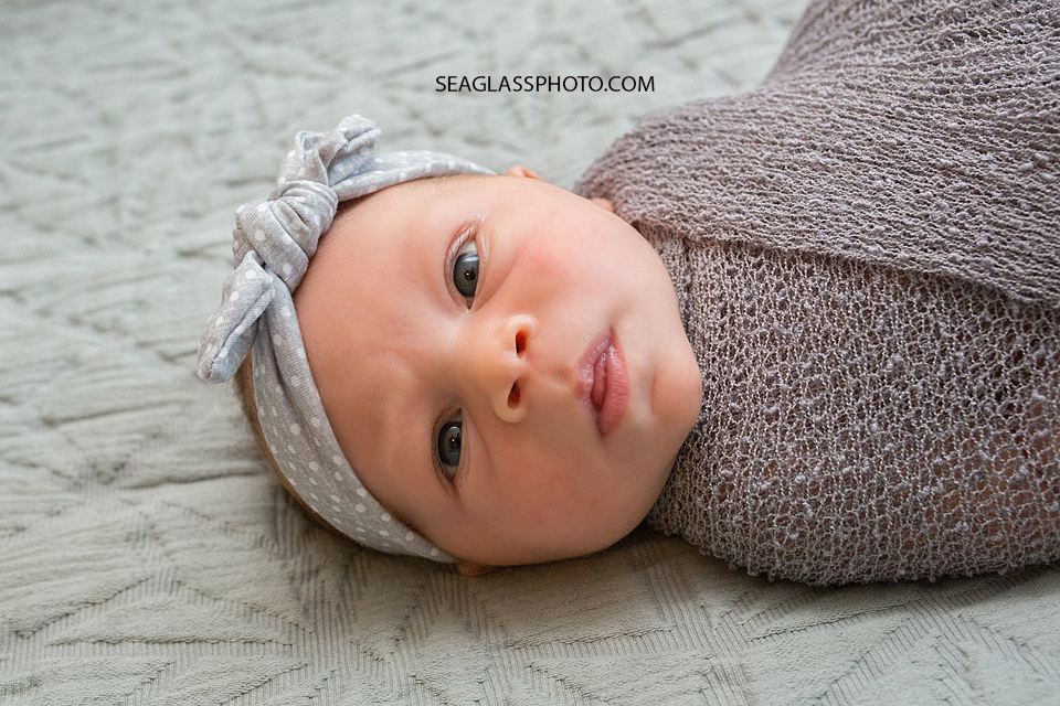 close up of newborn with eyes wide open wearing all grey
