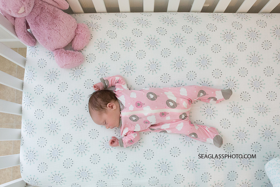 newborn baby girl laying in crib wearing kicki pants pajamas