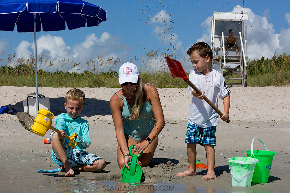 mother playing her two sons digging in the sand in Vero Beach Fl