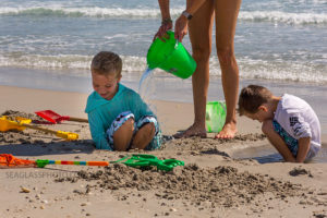 mom dumping a bucket of water on her son at the beach Vero Beach Florida