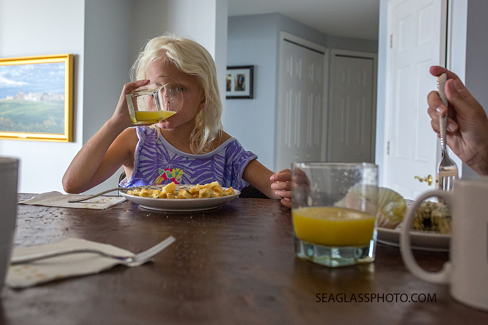 girl drinking orange juice at breakfast with waffles