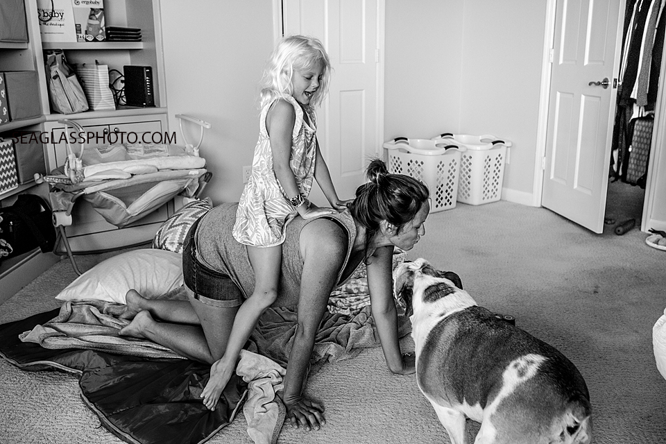 black and white photo of daughter playing with mom and dog