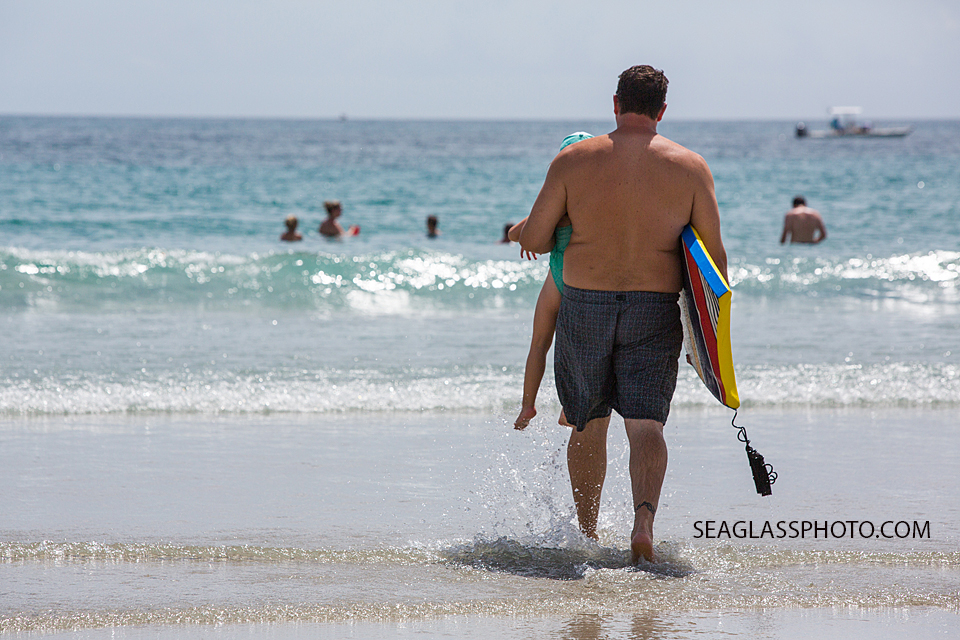 dad carrying daughter and boogie board into the ocean in Vero Beach Florida