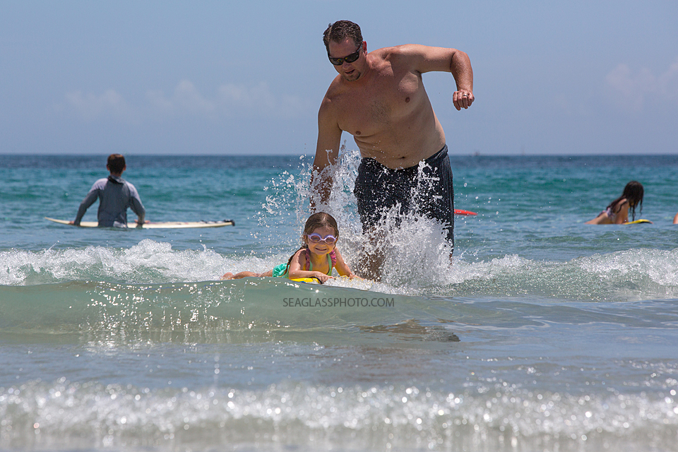 Father pushing daughter on the boogie board in Vero Beach Florida on a bright sunny day