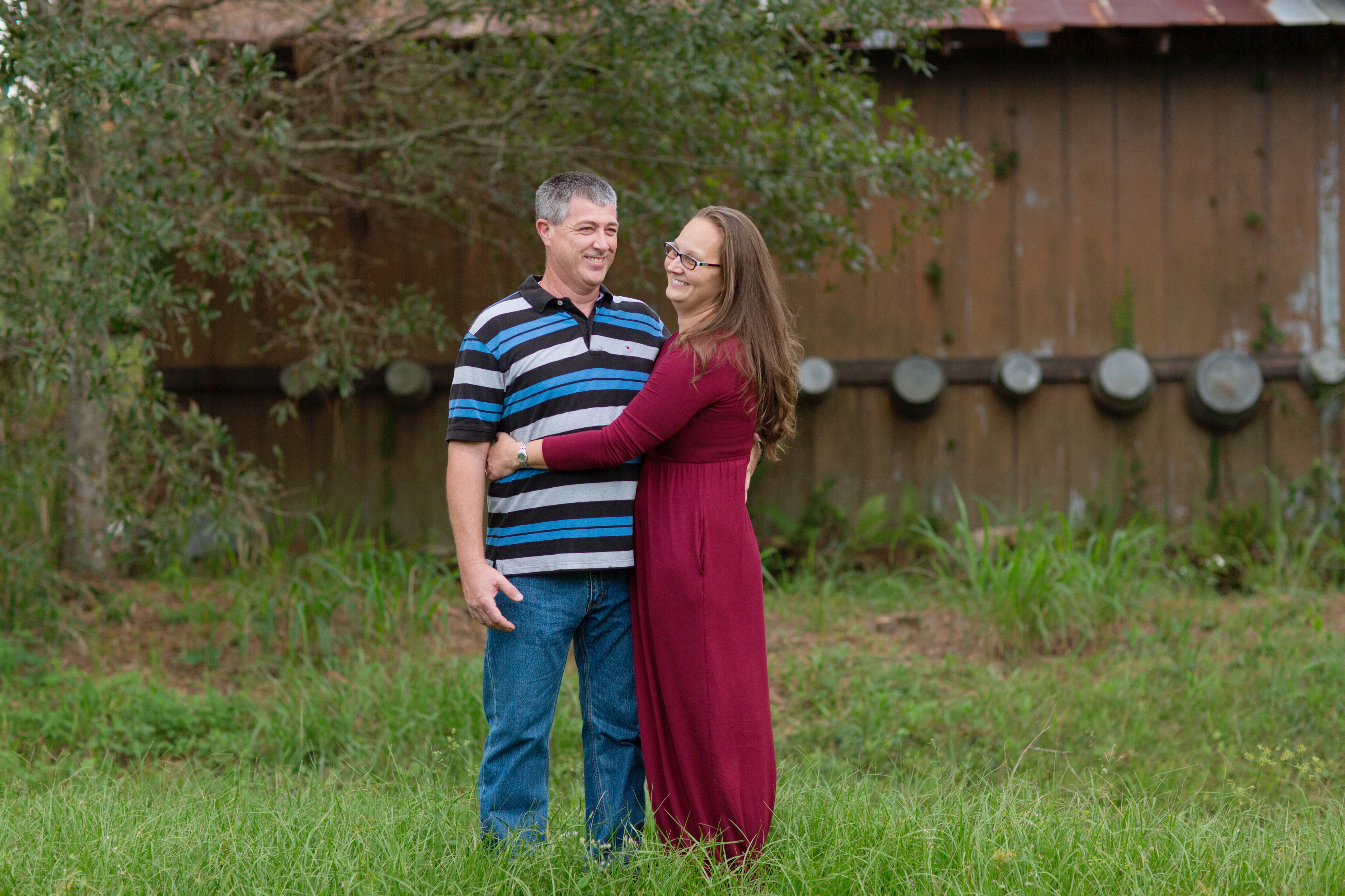parents hugging and smiling wearing fall colors at a barn in Vero Beach Florida