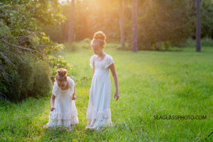 Sisters wearing long cream dresses picking flowers in a field in Vero Beach Florida