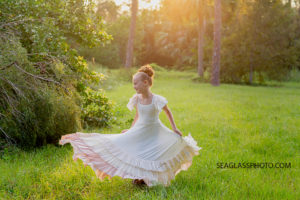 Girl wearing long cream dress twirling in a sunlit field in Vero Beach Florida