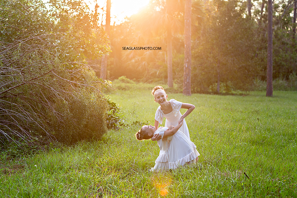 Sisters dancing in a field in Vero Beach Florida wearing long cream dresses