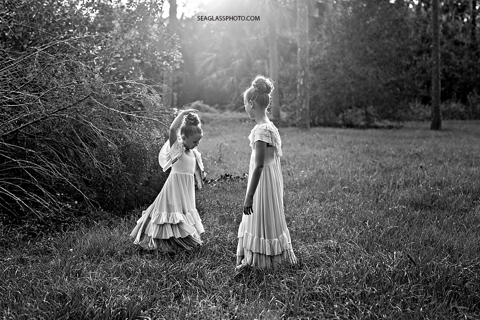 Black and White photo of sisters wearing long dresses dancing in a field