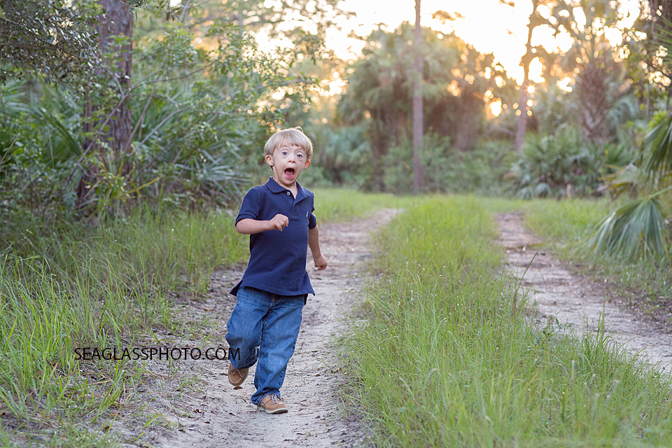 Boy wearing navy running through the woods with a big smile on his face