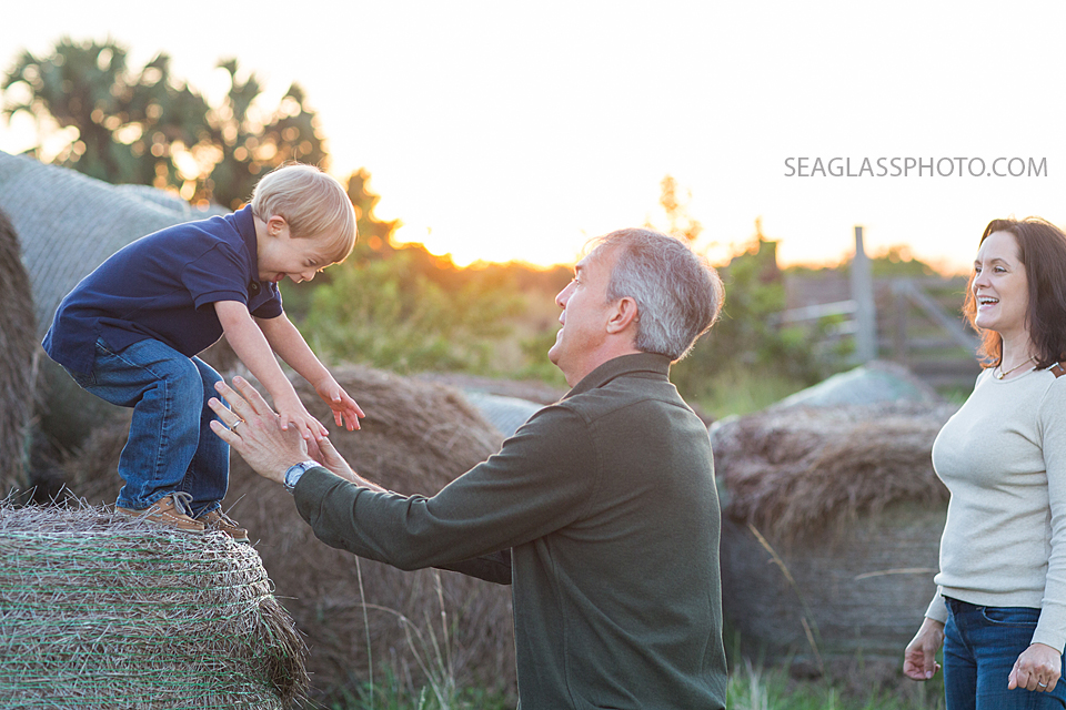 Boy jumping on a hay pile into his father's arms