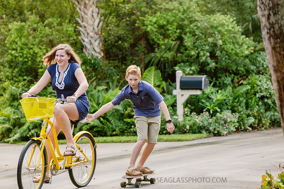boy skateboarding behind his sister on a yellow bicycle Vero Beach Florida family photography