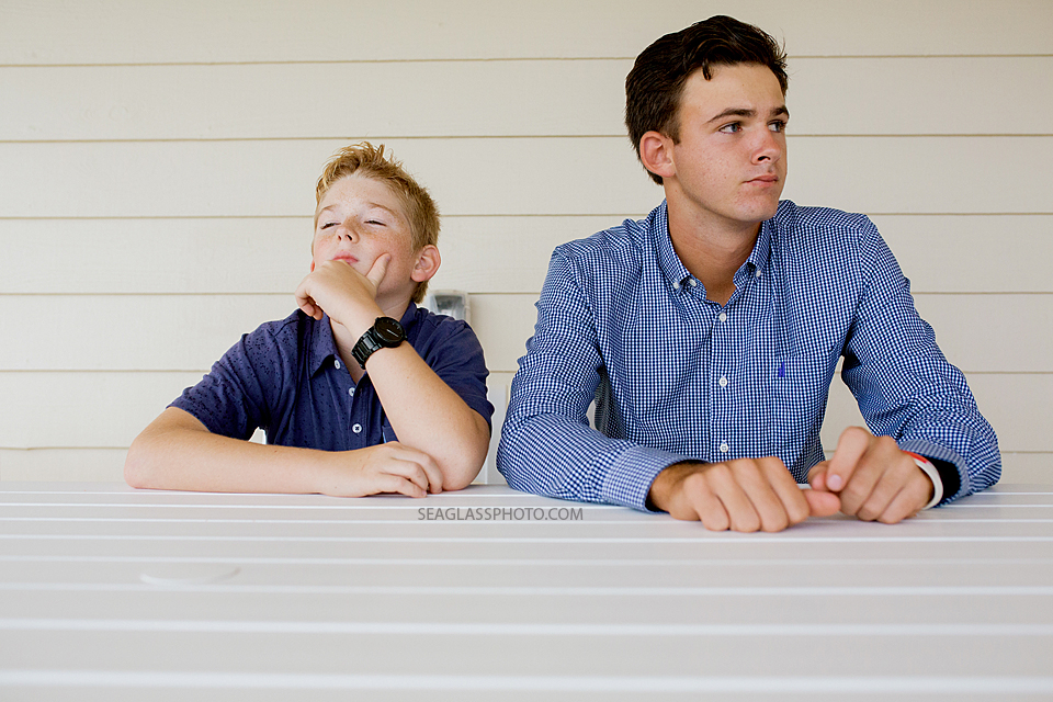 brothers sitting in a white room wearing navy and blue looking all serious Vero Beach Florida family photography