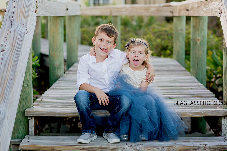 brother and sister making silly faces sitting on a boardwalk Vero Beach Florida family Photography