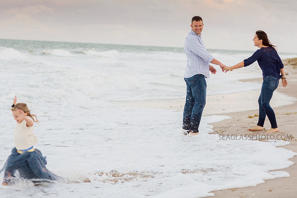 Parents walking on the beach watching their daughter run away wearing Wrare Doll Vero Beach Florida family Photography