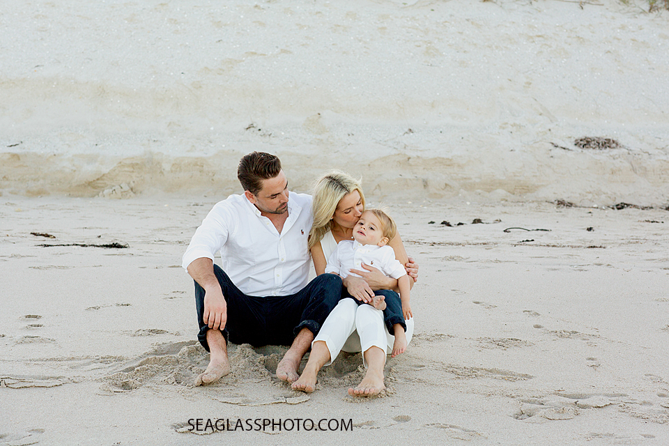 Family with toddler boy cuddling on the sand Orchid Island Beach Club in Vero Beach Florida