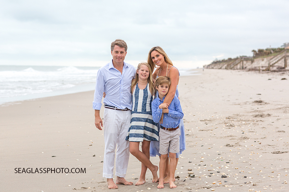 Family of four wearing white and light blue on the beach at Windsor Beach Club in Vero Beach Florida