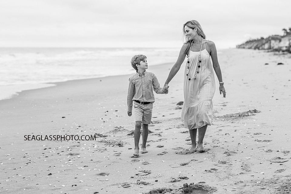 black and white photo of mother and son walking down the beach smiling at Windsor Beach Club in Vero Beach Florida