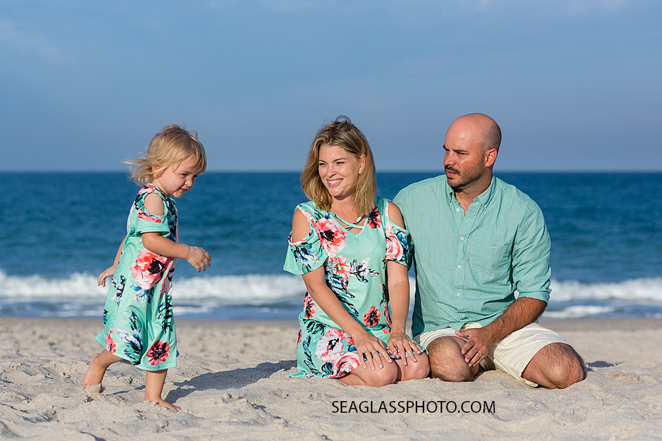 Parents watch their young daughter play with sand during family photos on the beach in Vero Beach Florida