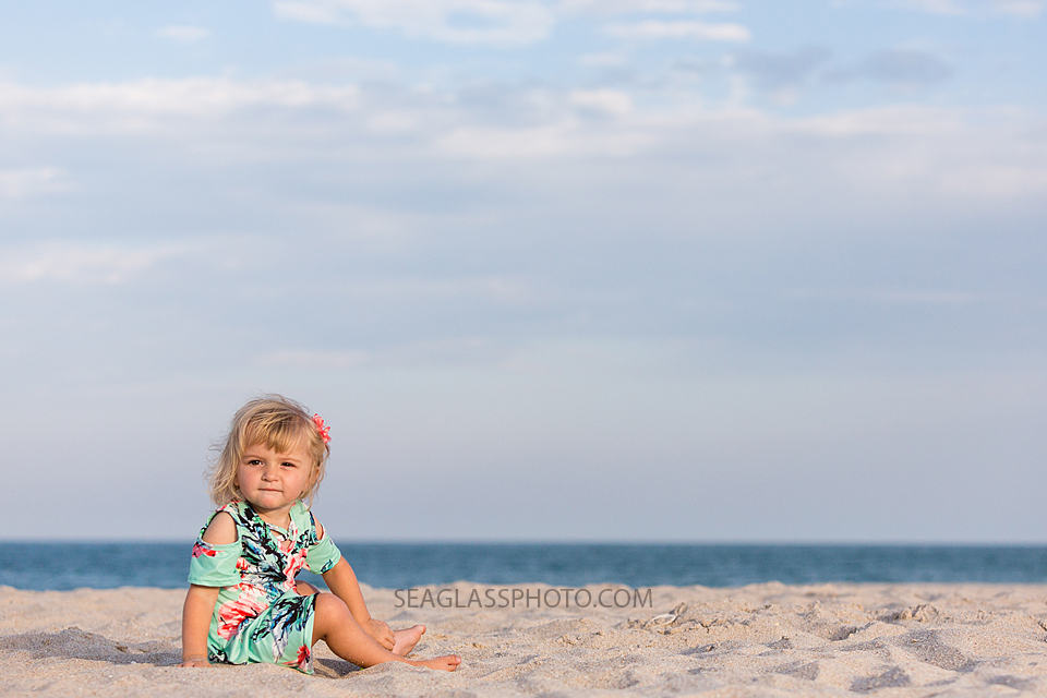 Young girl sitting in the beach with the ocean behind her in Vero Beach Florida