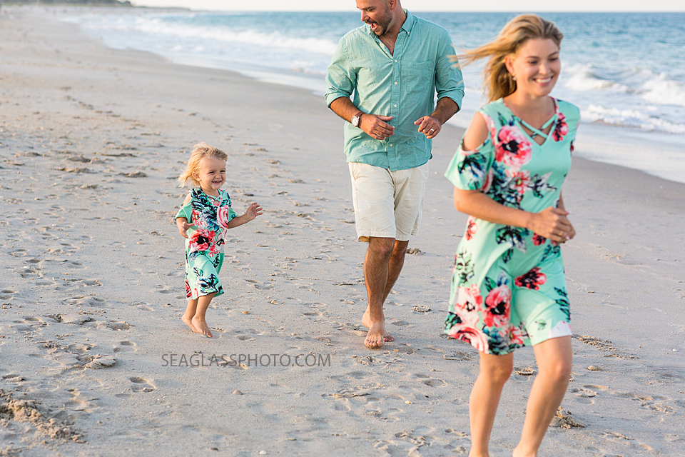 Parents playing with their daughter on the beach during family Photos in Vero Beach Florida