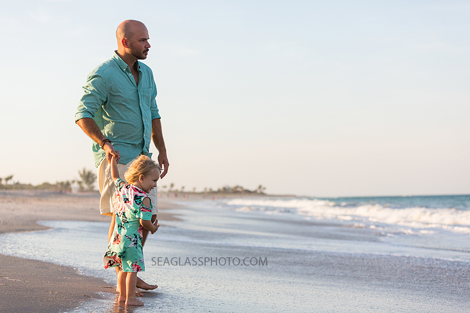 Father with young daughter looking out into the ocean during family photos in Vero Beach Florida