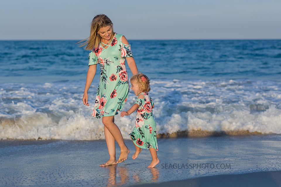 Mother and daughter walking on the beach together wearing matching outfits during family photos in Vero Beach Florida