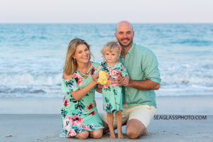 Family kneeling in front of the ocean on the beach during family photos in Vero Beach Florida