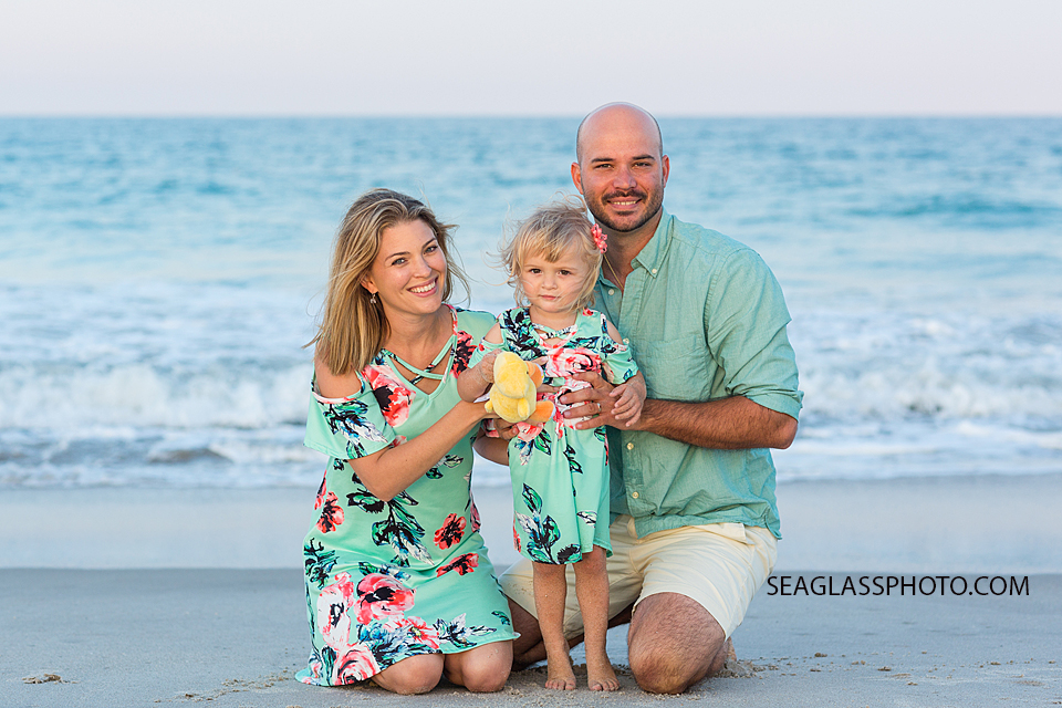 Family kneeling in front of the ocean on the beach during family photos in Vero Beach Florida