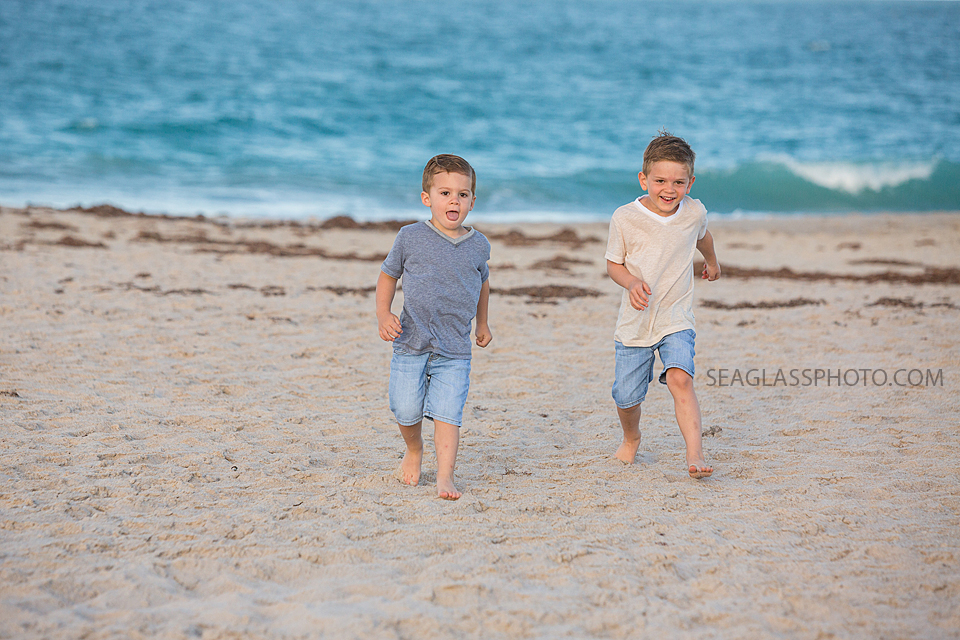 Two brothers running in the sand of the beach during maternity photos in Vero Beach Florida