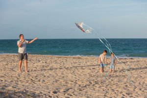 Father with two sons flying a kite on the beach in Vero Beach Florida