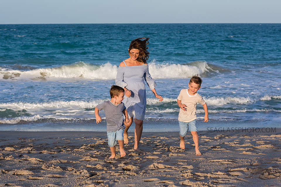 Pregnant mom walking with two sons on the beach wearing blue for maternity photos in Vero Beach Florida